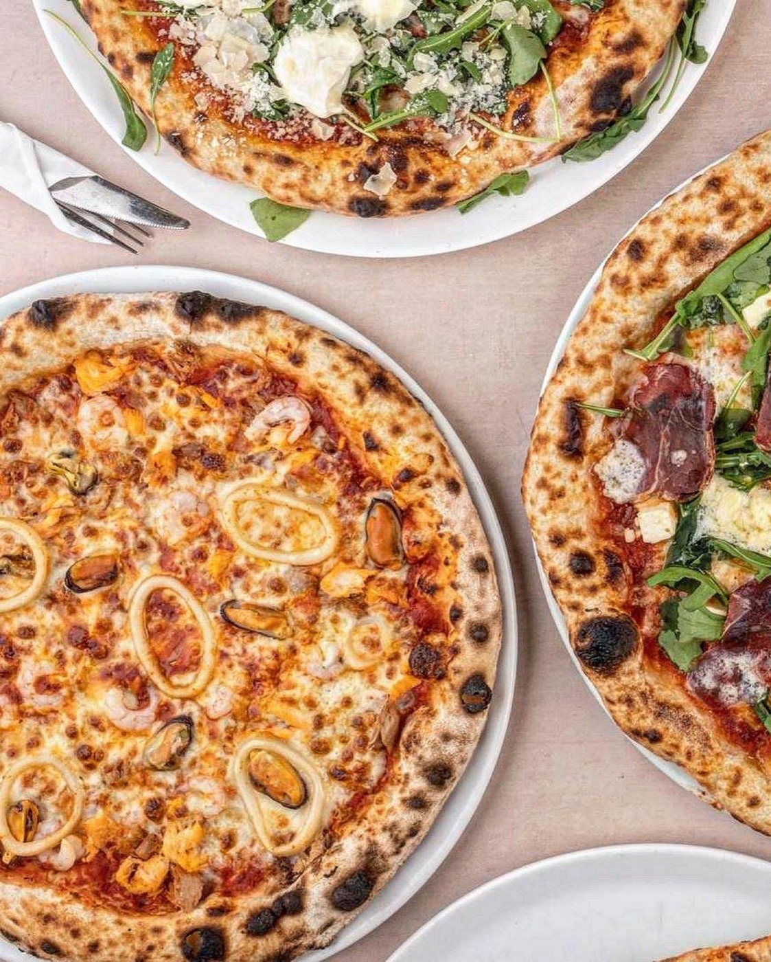 Kolme pizzaa pöydällä