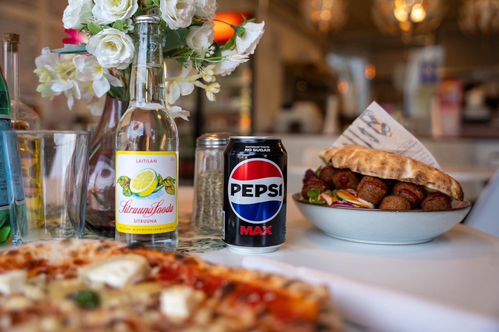 Pizza, falafel-pita ja juomat ravintolan pöydässä